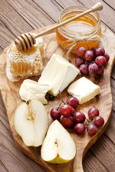 Cheese, grape and honey on wooden board — Stock fotografie