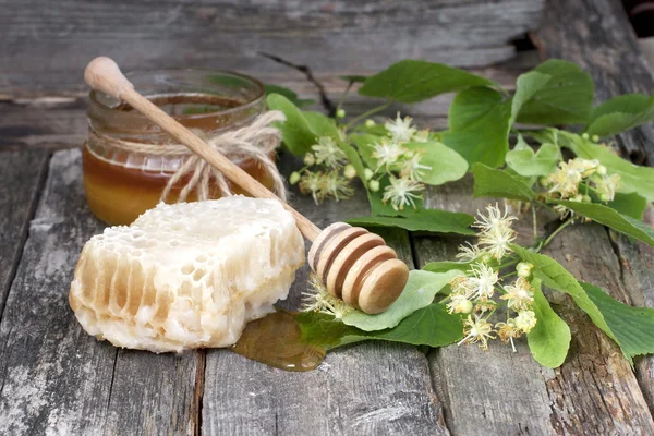 Glas vol blikjes honing op houten tafel — Stockfoto