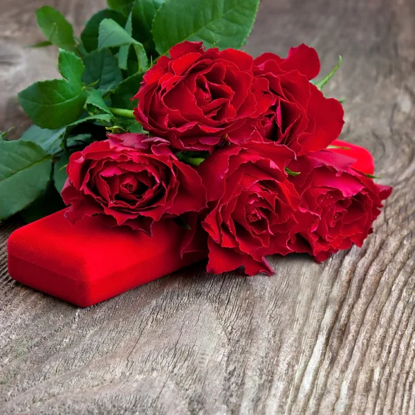 Rosas rojas y caja de regalo sobre fondo de madera —  Fotos de Stock
