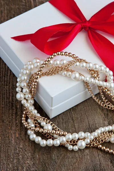 Red  gift box and necklace  on  wooden background.  Valentine's day, wedding or birthday  concept — Stock Photo, Image