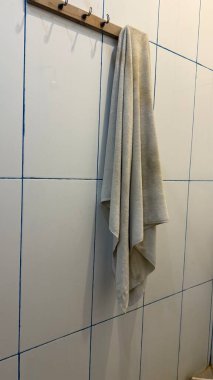 Banyodaki tahta kancaya sarılı bej havlu.