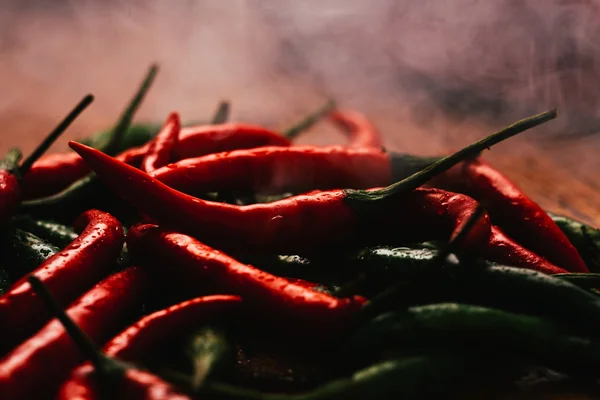 Red and green chili peppers close up on wooden background — Stock Photo, Image