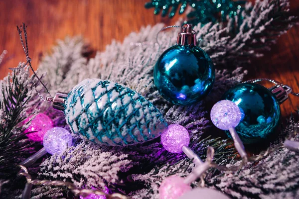 Fichtenzweige im Schnee violett blau-weiße Weihnachtskugeln auf dunklem Holzgrund — Stockfoto