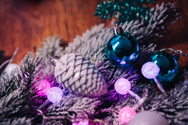 Fichtenzweige im Schnee violett blau-weiße Weihnachtskugeln auf dunklem Holzgrund — Stockfoto