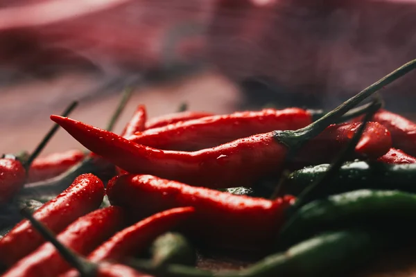 Red and green chili peppers close up on wooden background — Stock Photo, Image