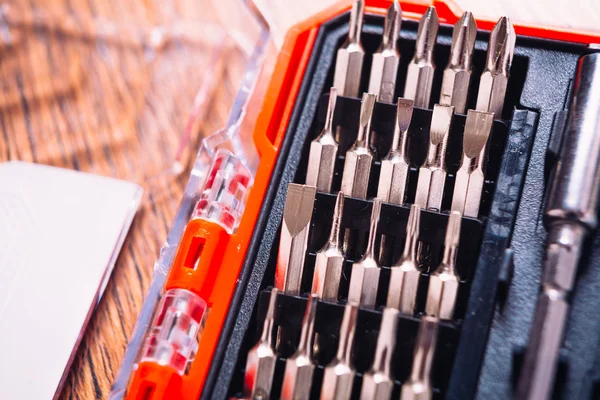 Set of nozzles for screwdriver in red box on wooden background — Stock Photo, Image