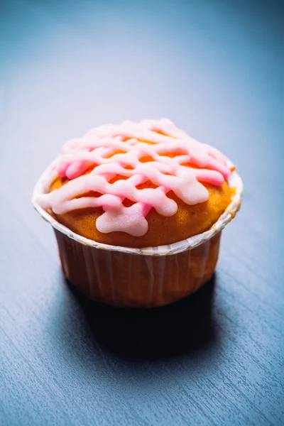 Pembe ahşap bir arka plan üzerinde buzlanma ile cupcake — Stok fotoğraf