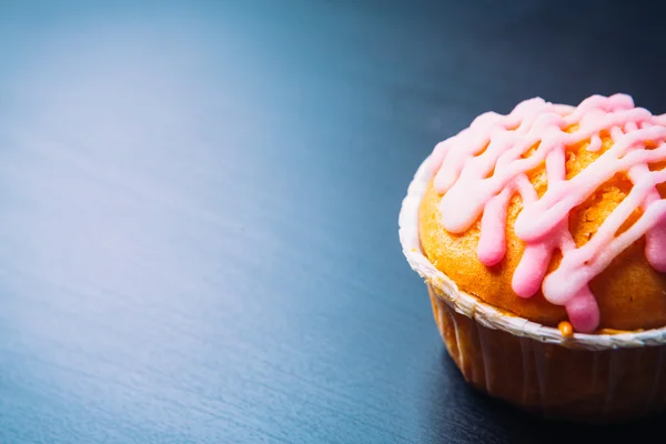 Cupcake com cobertura rosa em um fundo de madeira — Fotografia de Stock