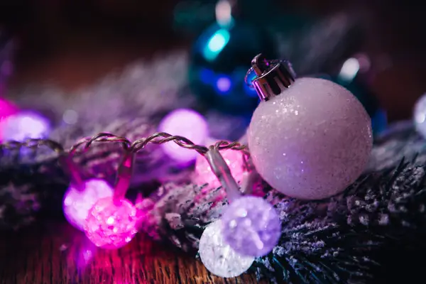 Fichtenzweige im Schnee violett blau-weiße Weihnachtskugeln auf dunklem Holzgrund — Stockfoto