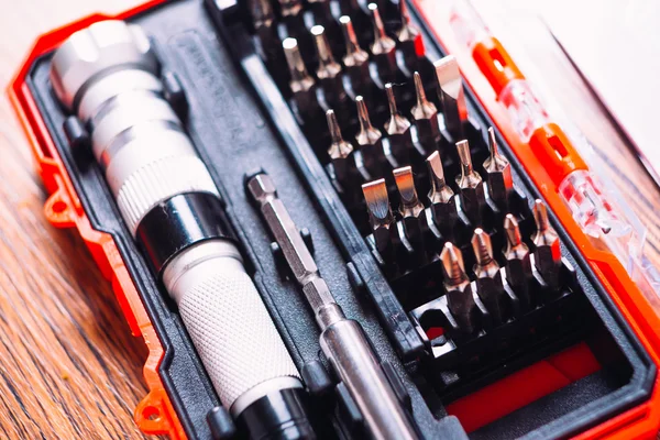 Set of nozzles for screwdriver in red box on wooden background — Stock Photo, Image