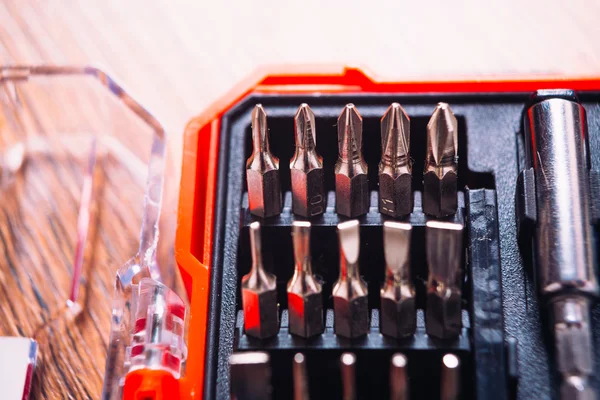 Set of nozzles for screwdriver in red box on wooden background — Stock Photo, Image