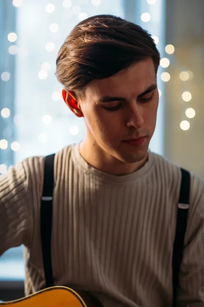 Young man sitting at home and playing guitar dramatic — Stock Photo, Image