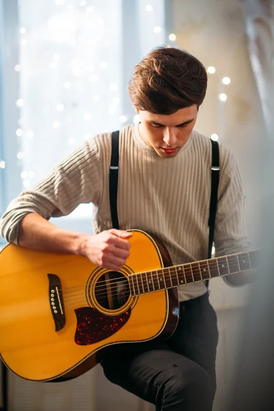 Young man sitting at home and playing guitar dramatic — Stock Photo, Image