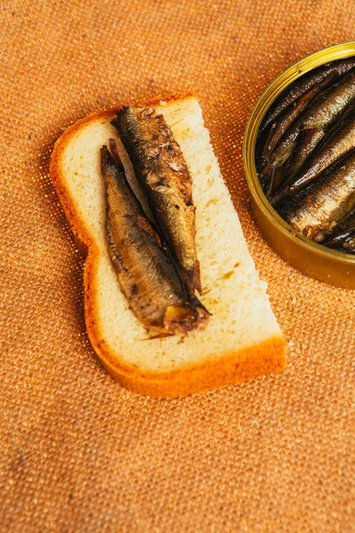 Open can and sandwich with of sprats on sackcloth background — Stock Photo, Image