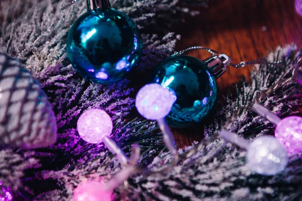 Ramas de abeto en la nieve violeta bolas de Navidad azul y blanco sobre fondo de madera oscura — Foto de Stock
