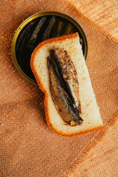 Open can and sandwich with of sprats on sackcloth background — Stock Photo, Image