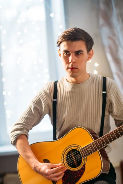 Young man sitting at home and playing guitar dramatic — Stock Photo, Image