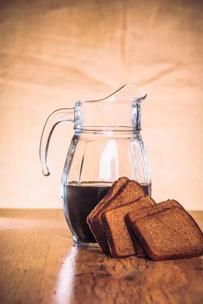 Russian brew in jug  and loaf of rye flour on wooden background — Stock Photo, Image