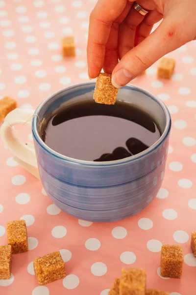 Modré šálek čaje a kusový cukr na růžovém pozadí — Stock fotografie