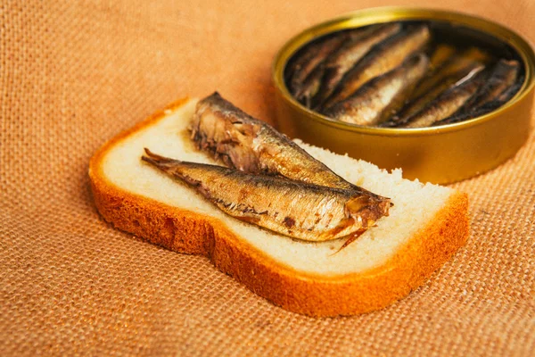 Open can and sandwich with of sprats on sackcloth background — Stock Photo, Image