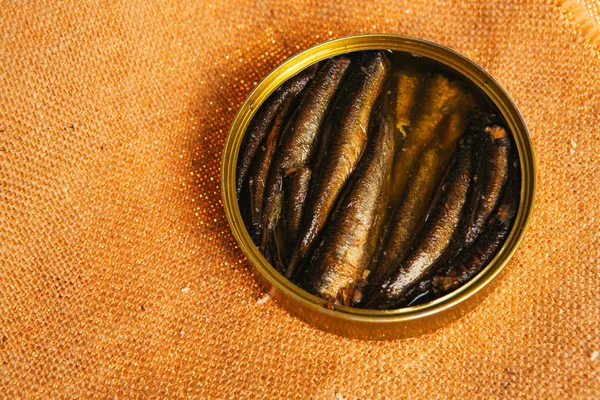 Open can with of sprats on sackcloth background — Stock Photo, Image