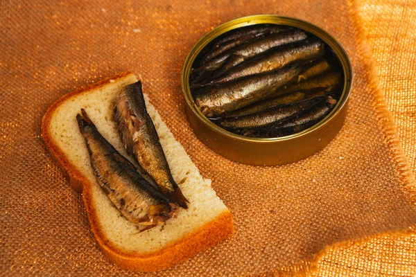 Open can and sandwich with of sprats on sackcloth background — Stock Photo, Image