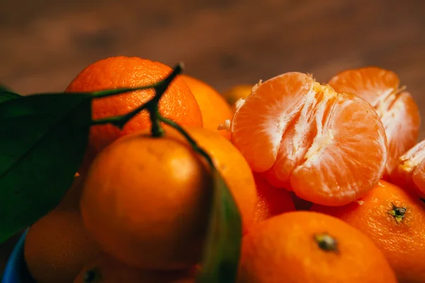 Frisch geschälte Mandarinensegmente in Nahaufnahme vor einem Hintergrund orangefarbener Mandarinen — Stockfoto