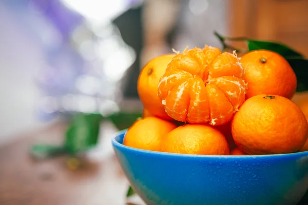 Viele frische Mandarinen in einer blauen Schüssel, die auf einem Holztisch steht — Stockfoto