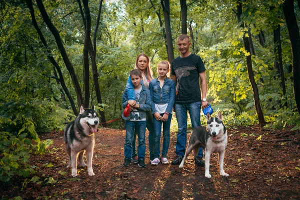 Rodina s dětmi a psy husky v lese — Stock fotografie