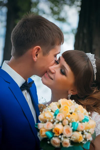 Поцелуи невесты и жениха на фоне деревьев — стоковое фото
