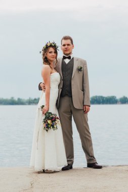 Genç damat ve gelin ayakta nehrin arka plan üzerinde sarılma.