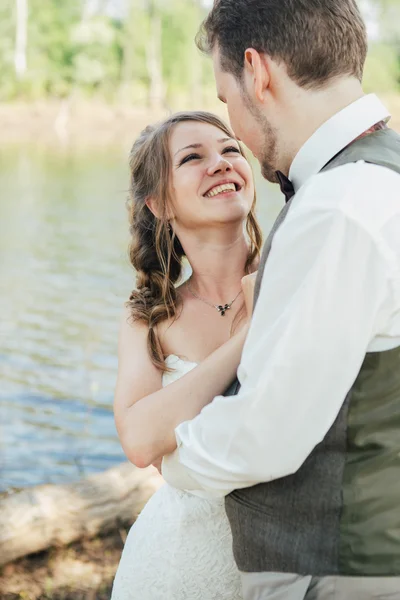 Bride and groom standing arm in  against the background grass  lakes — Stock Photo, Image