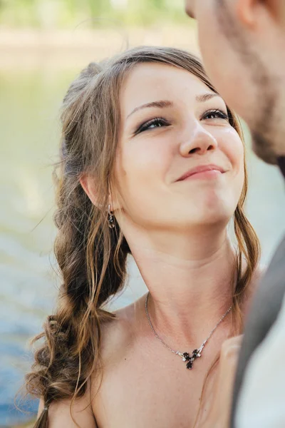 Bride and groom standing arm in  against the background grass  lakes — Stock Photo, Image