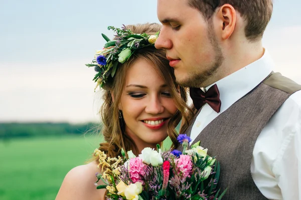 Retrato de la novia y el novio con un ramo en el campo verde — Foto de Stock