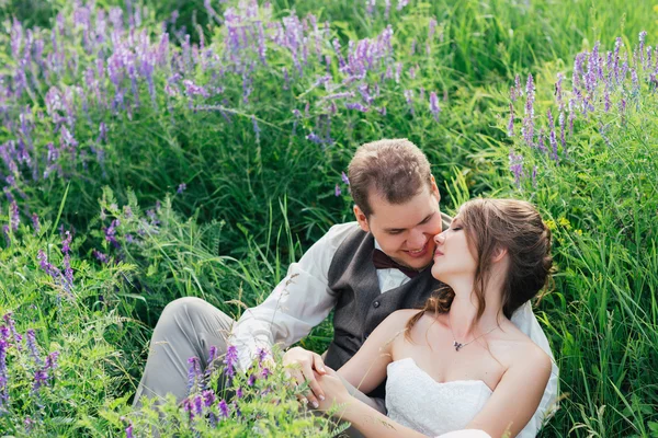 Retrato da noiva e do noivo descansando sobre um fundo de lavanda — Fotografia de Stock