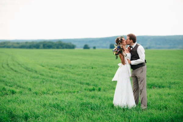 Gli sposi con un bouquet sul campo verde — Foto Stock