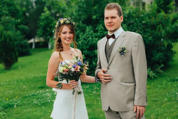 Young happy bride and groom on the background of greenery — Stock Photo, Image