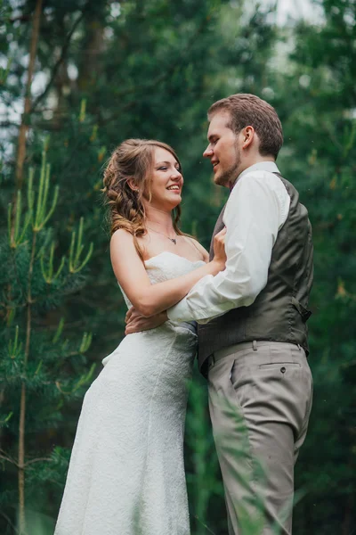 Noiva e noivo estão abraçando contra a floresta de fundo — Fotografia de Stock