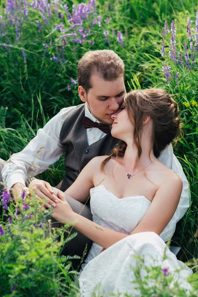 Retrato da noiva e do noivo descansando sobre um fundo de lavanda — Fotografia de Stock