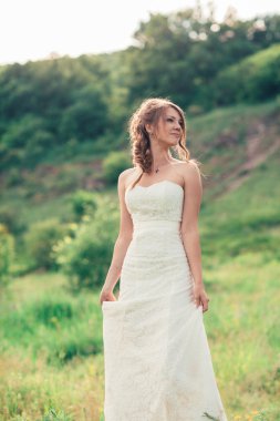 Gelin çimlerin ve dağların arkasında duruyor.