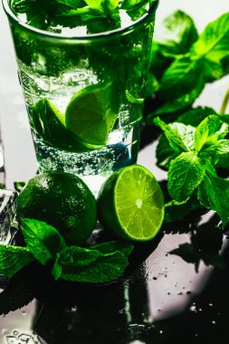 Bir bardak limonlu mojito ve arka planda naneli buzlu dondurma.