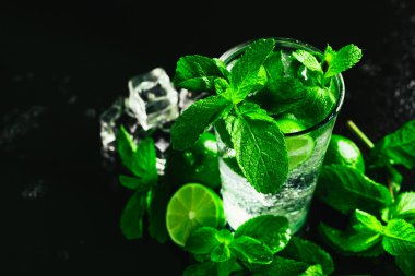 Bir bardak limonlu mojito ve arka planda naneli buzlu dondurma.