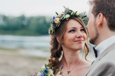 Genç damat ve gelin ayakta nehrin arka plan üzerinde sarılma.