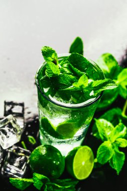 Bir bardak limonlu mojito ve arka planda naneli buzlu dondurma.