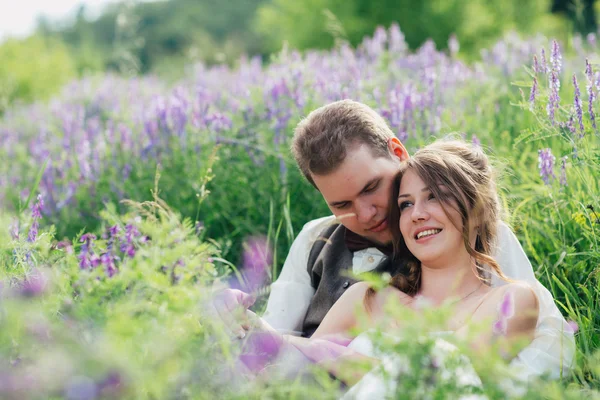 Retrato da noiva e do noivo descansando sobre um fundo de lavanda — Fotografia de Stock