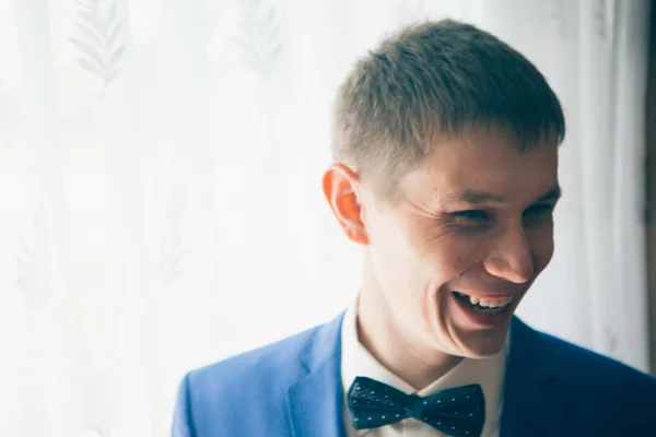 Young groom stands on the background of a window — Stock Photo, Image