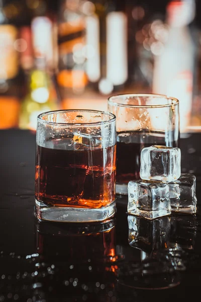 two glasses of whiskey on a blurred background bar