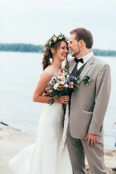 Young groom and bride standing hugging on the background of the river — Stock Photo, Image