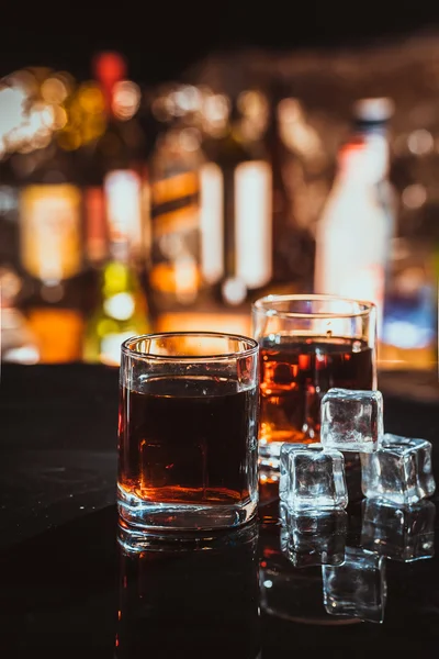 Two glasses of whiskey on a blurred background bar — Stock Photo, Image