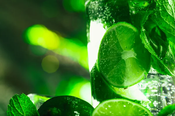 Vetro di mojito con calce e menta primo piano cubetto di ghiaccio su sfondo scuro — Foto Stock